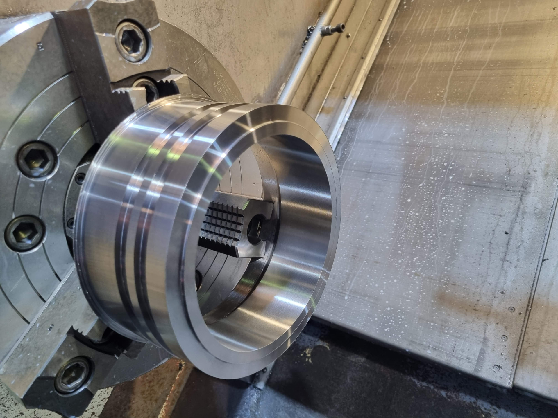 Machined steel casing connection component held in a lathe chuck