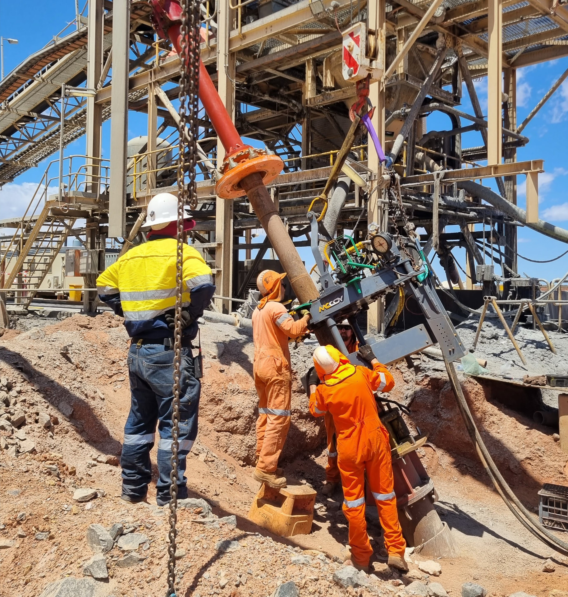 Crews guiding lined casing into position with lifting equipment on site